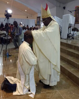 Bishop Yves-Marie Pean, CSC, lays hands on Deacon Sagesse during his priestly Ordination