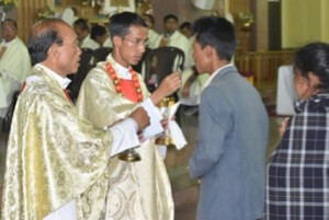 Newly Ordained Fr Bilingshar Syienlieh, CSC, gives communion