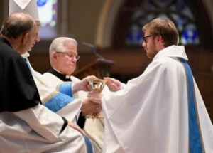 Newly ordained Fr Michael Thomas, CSC, receives the chalice and paten