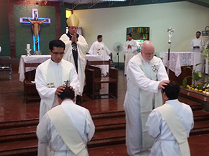 Bishop Izaguirre prays as the concelebrants lay hands on Elmer and Julio